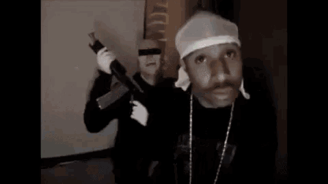 a man is holding a gun next to a green bentley car .