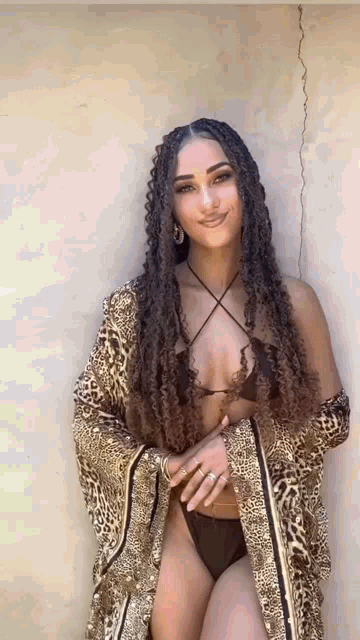 a woman with dreadlocks is wearing a bikini and a leopard print robe .