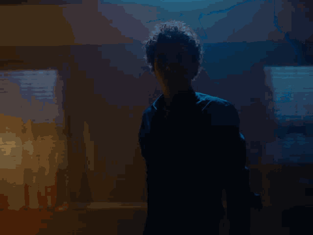 a man stands in a dark room with blue lights shining through the ceiling