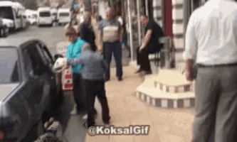 a group of people are walking down a sidewalk in front of a car .