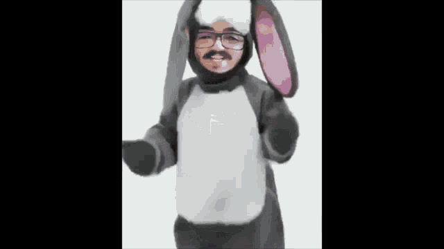 a man with glasses and a mustache is wearing a bunny costume and dancing .