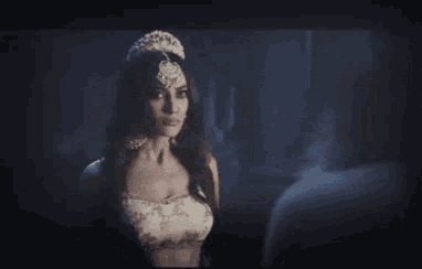 a woman with a crown on her head is standing in the dark