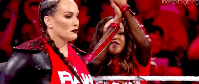 a couple of women standing next to each other in a wrestling ring holding hands .