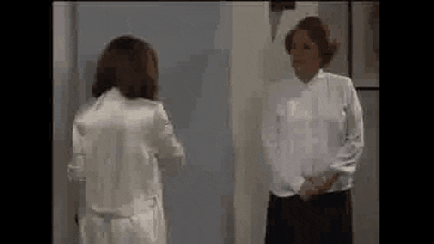 two women are standing next to each other in a room .
