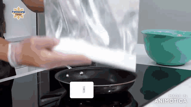 a person is pouring something into a frying pan with the letter h on the bottom