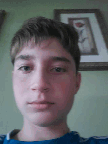 a close up of a young man 's face with a framed picture behind him