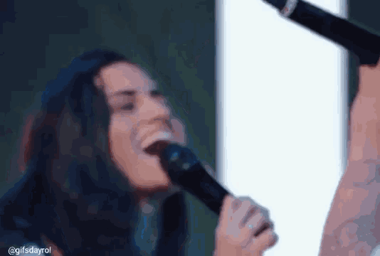 a woman is singing into a microphone and laughing .