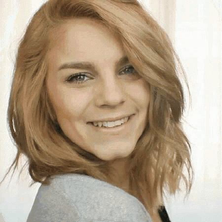 a woman with blonde hair is smiling and wearing a grey shirt