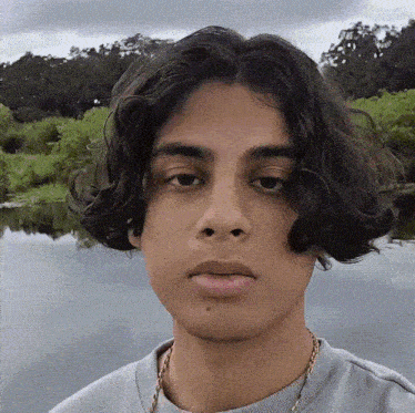 a young man with long curly hair is looking at the camera