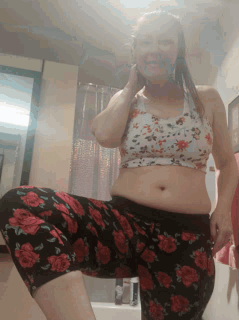 a woman in a floral top and floral shorts stands in front of a shower curtain