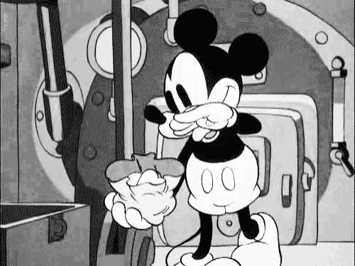 a black and white cartoon of mickey mouse eating a donut in a room .
