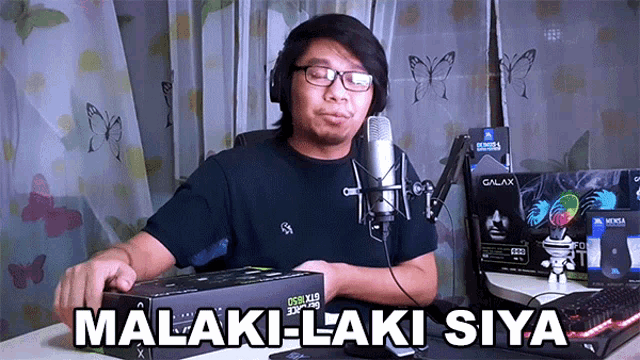 a man sitting in front of a microphone with the words malaki-laki siya written on the table