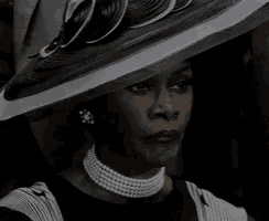 a woman wearing a black and white hat and pearls