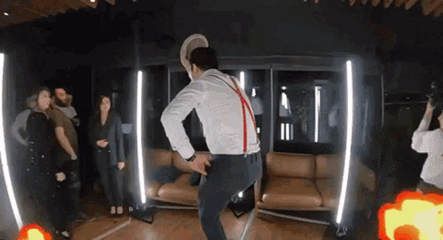 a man in a hat and suspenders is dancing in a room