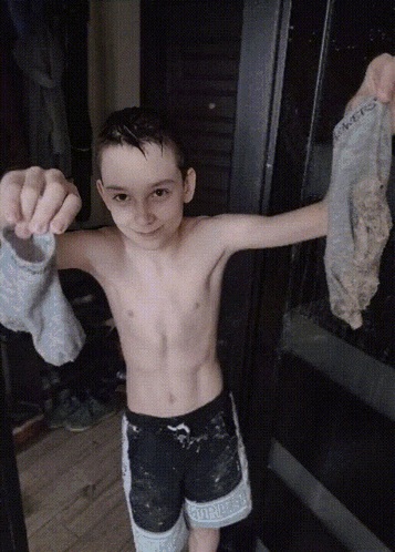 a shirtless young boy holds up a pair of socks with the word socks on them