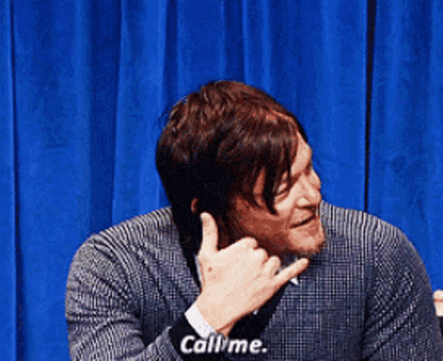 a man in a plaid shirt and tie is making a hand gesture that says call me