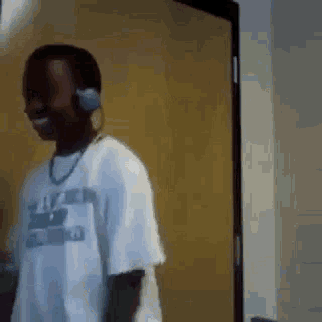 a young boy wearing headphones and a white shirt is standing in front of a door .