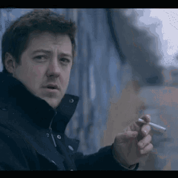 a man in a black jacket is holding a cigarette in his hand .