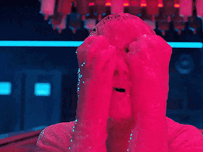 a person is covered in pink slime and covering their eyes with their hands .