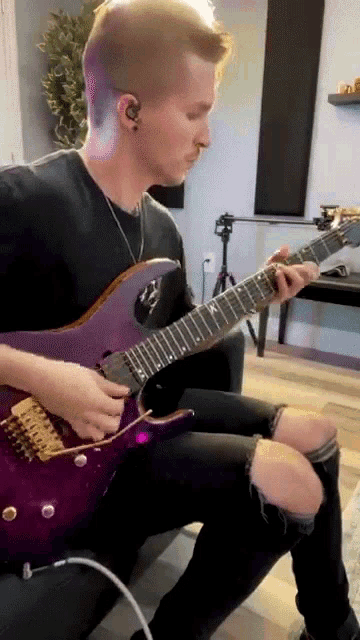 a man is playing a purple guitar in a room