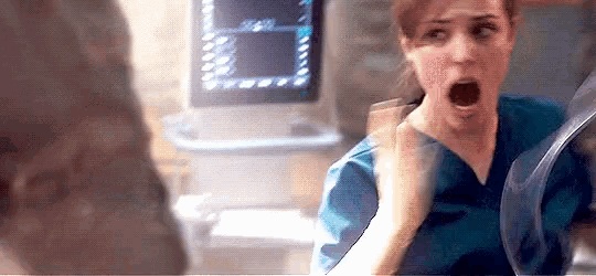 a woman in a scrub is screaming at a man in a hospital room .