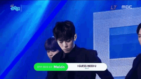 a man in a black suit is standing on a stage with a green button that says i guess i need u on it