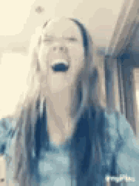 a woman with long hair is laughing with her mouth open and her eyes closed .