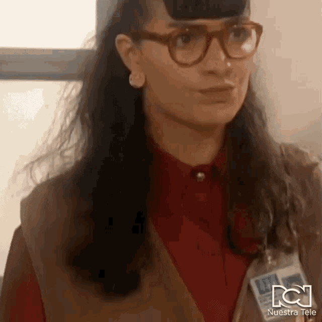 a woman wearing glasses , a vest , and a name tag .