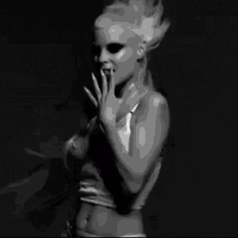 a black and white photo of a woman in lingerie dancing in a dark room .