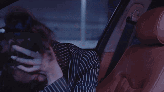 a woman in a car with her mouth open and her hands on her head with the letter f on her jacket