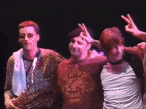 a man wearing a red shirt that says nitro planet is giving a peace sign