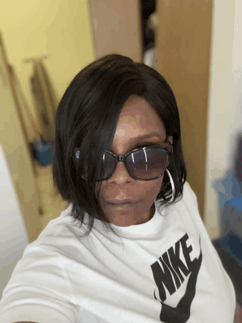 a woman wearing sunglasses and a white nike t-shirt