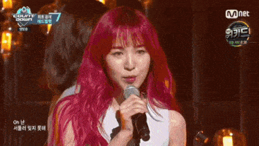 a group of women are standing on a stage with a mnet logo in the background