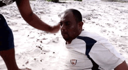 a man in a white shirt with the word arsenal on it is laying in the sand