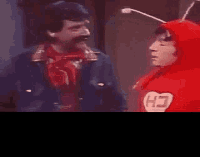 a man in a red hoodie is talking to another man in a red hoodie .