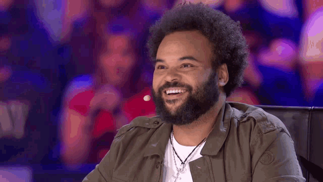 a man with a beard and afro is sitting in front of a microphone .