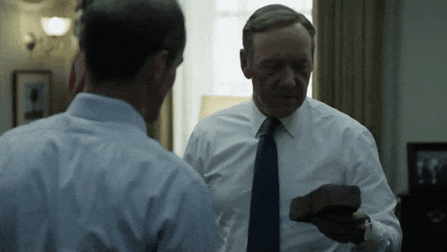 a man in a white shirt and blue tie is holding a piece of wood