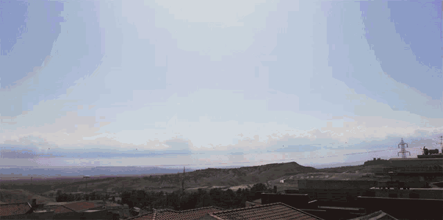 a blue sky with a few clouds and a few buildings in the foreground