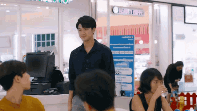 a man in a black shirt is standing in front of a counter in a mall .