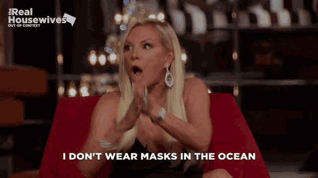 a woman is sitting on a red couch with her mouth open and says i don 't wear masks in the ocean