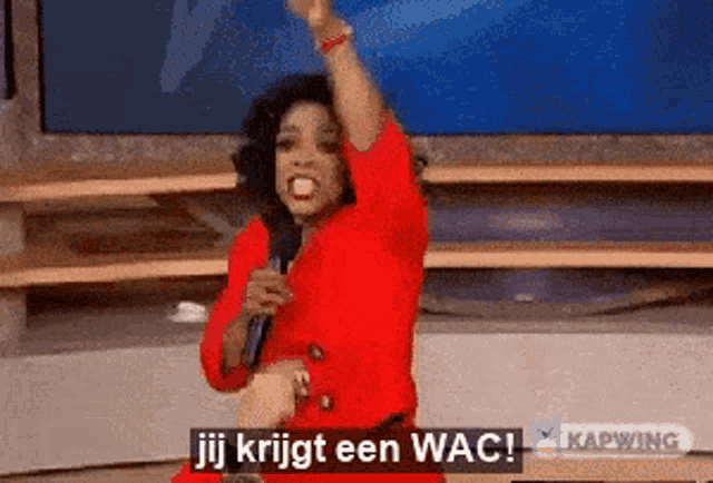 a woman in a red dress is holding a microphone and says jij krijgt een wac !