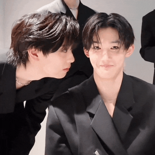 a man in a black suit is looking at another man