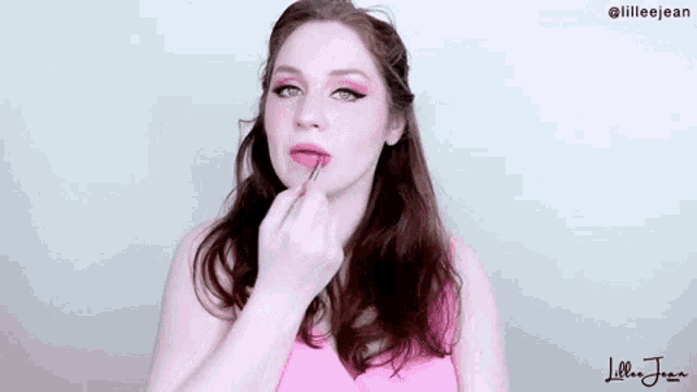 a woman is applying lipstick with a brush .