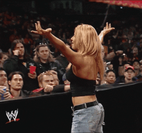 a woman stands in front of a crowd with her arms outstretched in front of a w logo