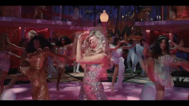 a group of women are dancing in a pink room
