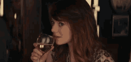 a woman is holding a glass of wine in her hand and drinking it .