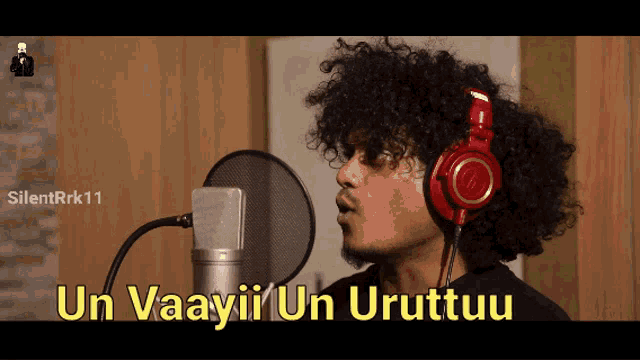 a man wearing headphones singing into a microphone with the words un vaayii un uruttuu