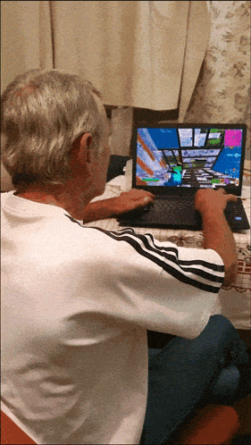 an elderly man is playing a video game on a laptop