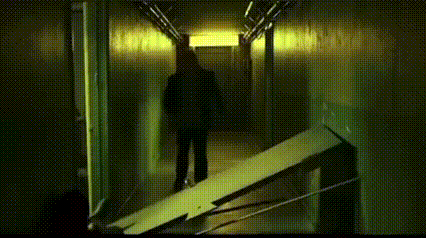 a silhouette of a person walking down a hallway with a yellow light .