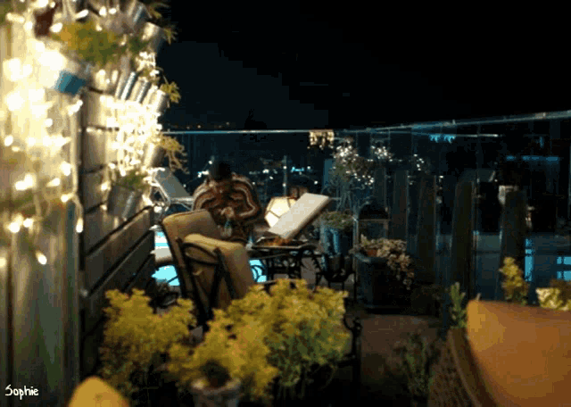 a man sits on a chair on a balcony with the name sophie on the bottom left